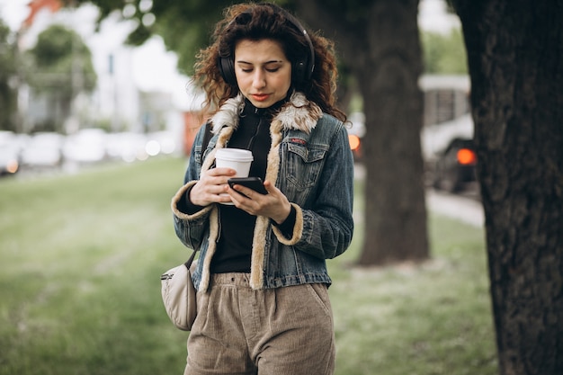 Mujer joven con escuchar música y beber café