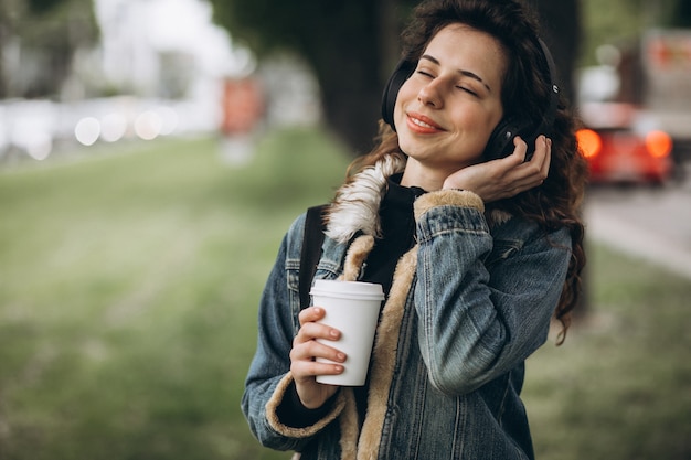 Mujer joven con escuchar música y beber café