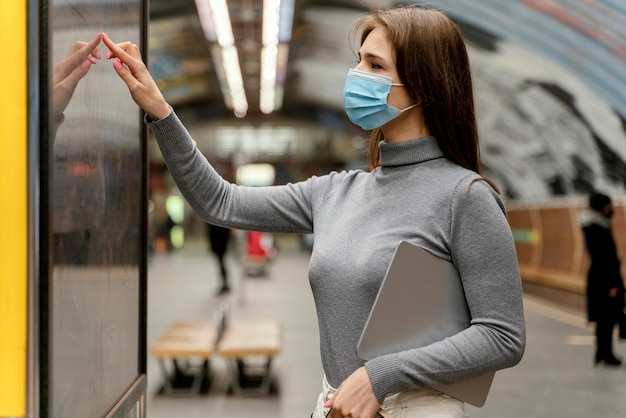 Foto gratuita mujer joven esperando en una estación de metro con una tableta