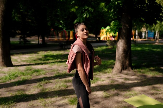 La mujer joven está descansando después de trotar en el parque.