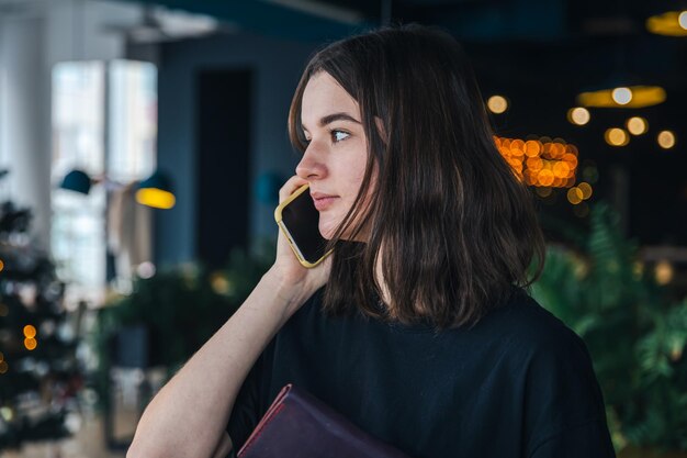 Una mujer joven está hablando por teléfono con una billetera en las manos.