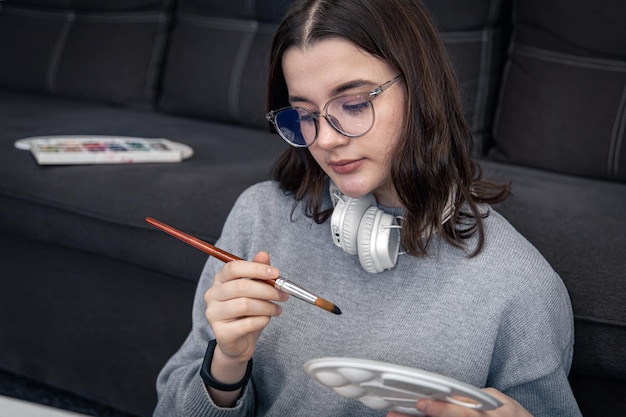 Una mujer joven está pintando un cuadro en un lienzo mientras está sentada
