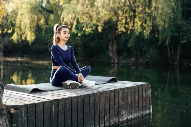 Mujer joven en una estera de yoga relajarse al aire libre