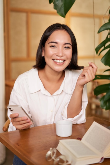 Mujer joven con estilo en la cafetería con café con teléfono móvil riendo y sonriendo estilo de vida y gente