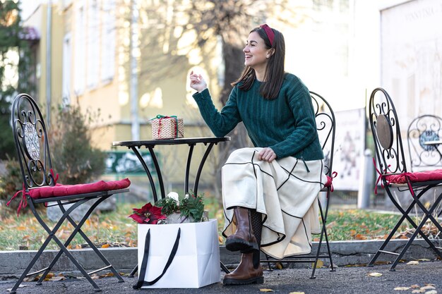 Mujer joven con estilo con cajas de regalo, concepto de compras navideñas, compra de regalos para familiares y amigos.