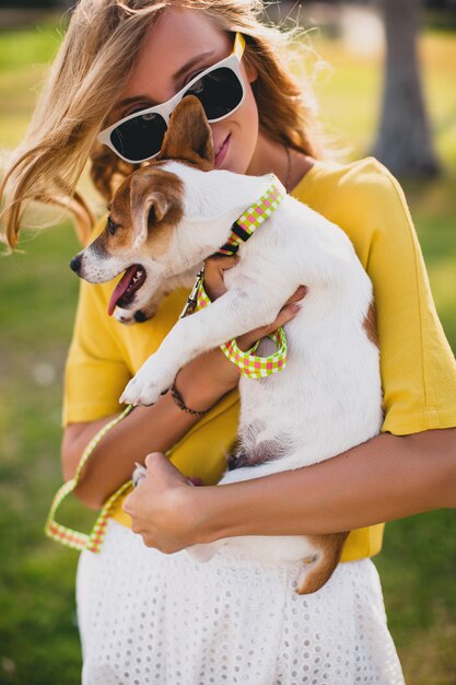 Mujer joven con estilo hipster sosteniendo caminar y jugar con perro