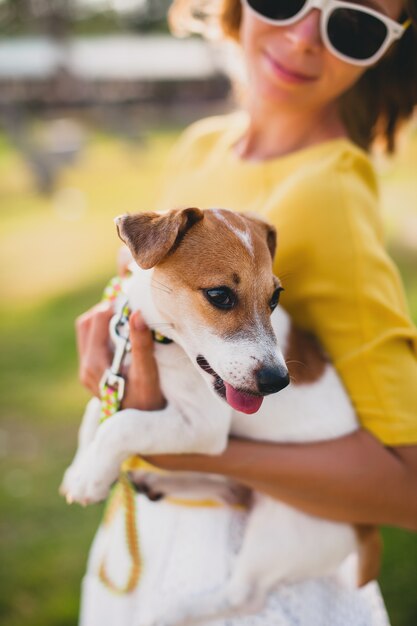 Mujer joven con estilo hipster sosteniendo caminar y jugar con perro