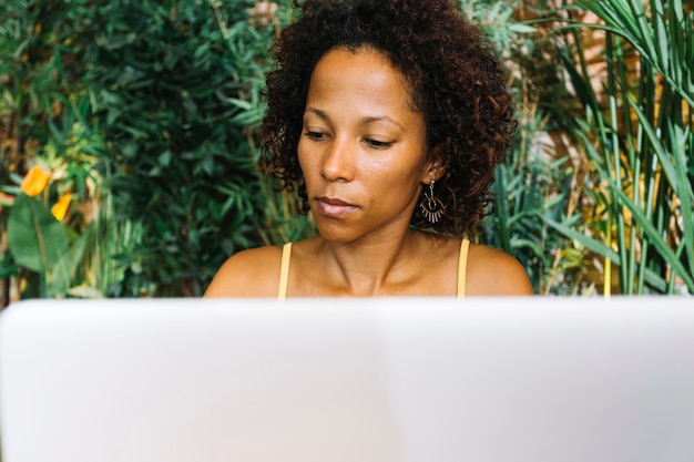 Foto gratuita mujer joven con estilo que mira la computadora portátil