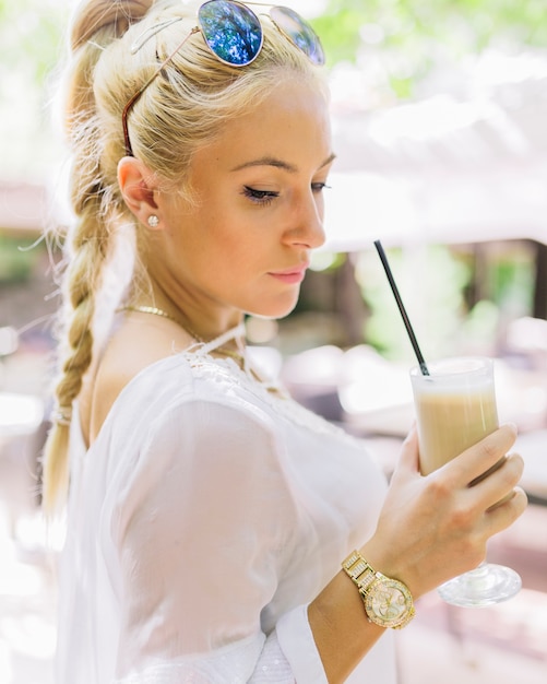 Foto gratuita mujer joven con estilo que sostiene el vidrio de latte macchiato