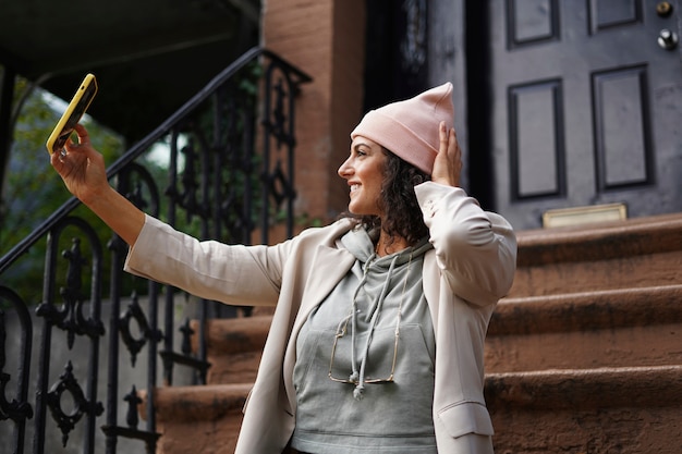 Mujer joven con estilo tomando selfie mientras explora la ciudad