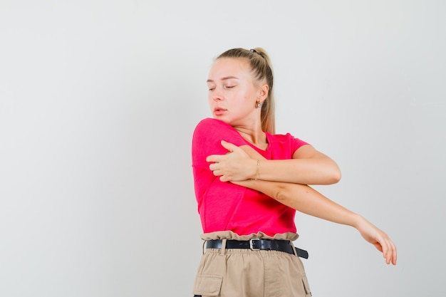 Foto gratuita mujer joven estirando los brazos en camiseta, pantalón y mirando atractivo, vista frontal.