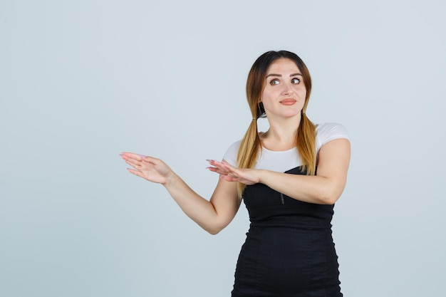 Mujer joven estirando las manos hacia la izquierda y luciendo lindo