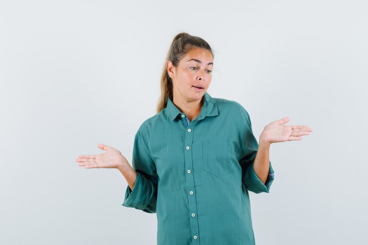 Foto gratuito mujer joven estirando las manos de manera interrogante en blusa verde y mirando perplejo