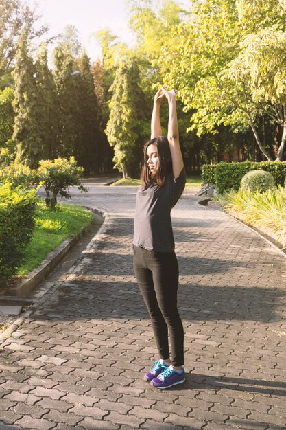 Mujer joven estirando sus brazos al aire libre