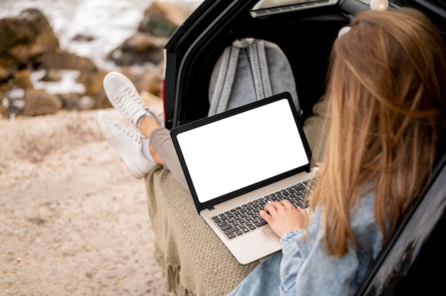 Mujer joven, examinar, computadora portátil, en, viaje por carretera