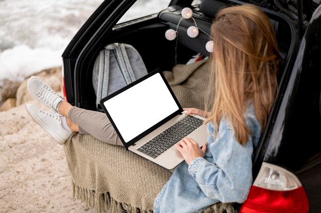 Mujer joven, examinar, computadora portátil, en, viaje por carretera