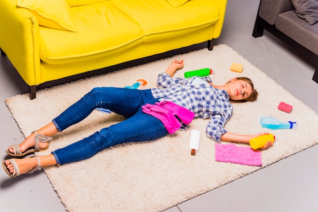 Mujer joven exhausta tras limpiar la casa