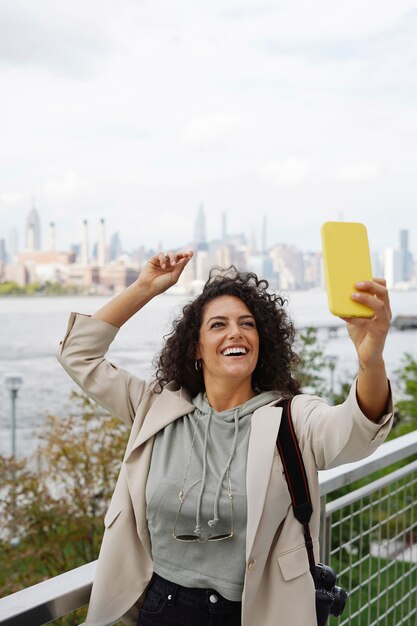 Mujer joven explorando la ciudad mientras toma selfie con smartphone