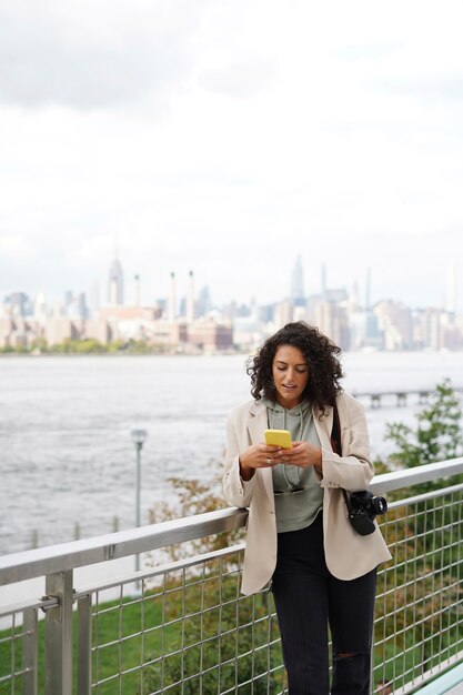 Mujer joven explorando la ciudad mientras usa un teléfono inteligente