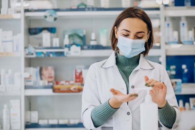 Mujer joven farmacéutico desinfectar las manos con sanitazer