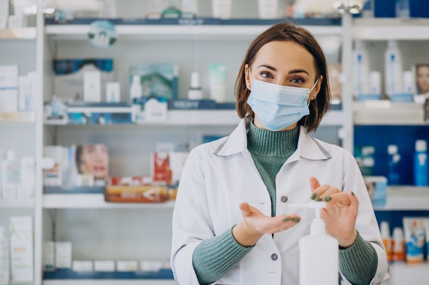 Mujer joven farmacéutico desinfectar las manos con sanitazer