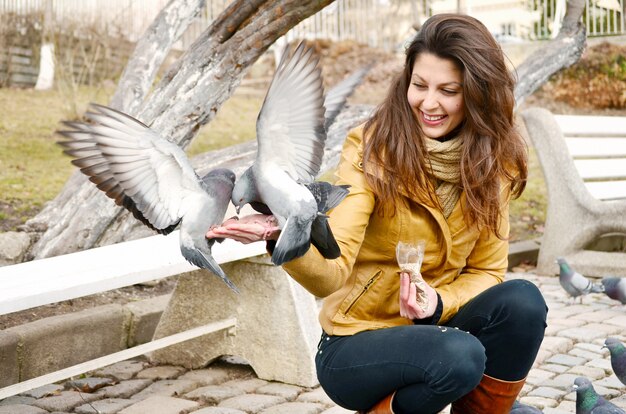 Mujer joven feliz alimentando palomas