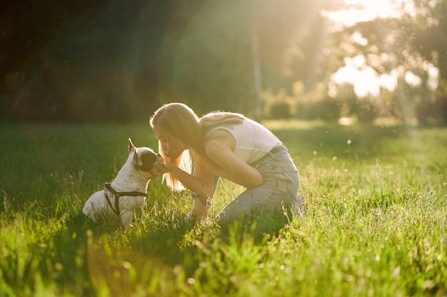 Mujer joven feliz besando a bulldog francés en el parque