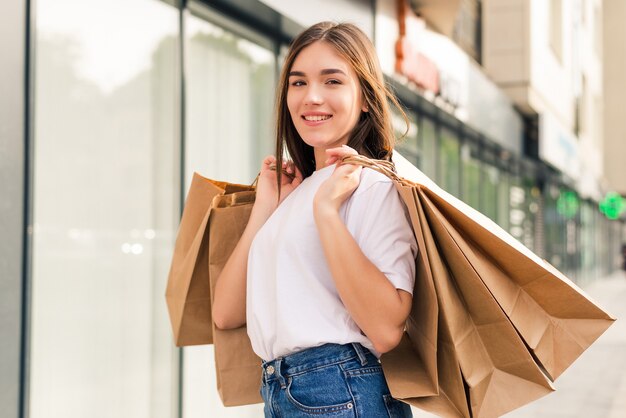Mujer joven feliz con bolsas de compras caminando en la calle.