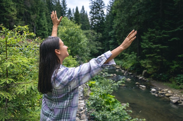 Mujer joven feliz en el bosque en las tierras altas cerca del río