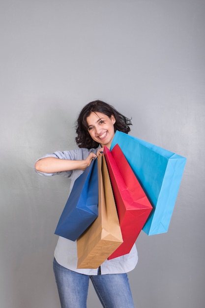 Mujer joven feliz en camisa con los bolsos de compras