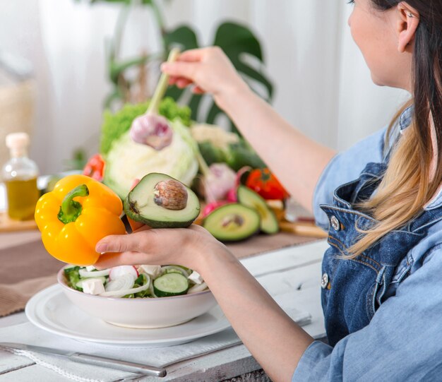 Mujer joven y feliz comiendo ensalada en la mesa