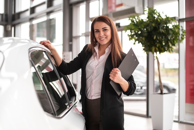 Foto gratuita mujer joven feliz en concesionario de automóviles