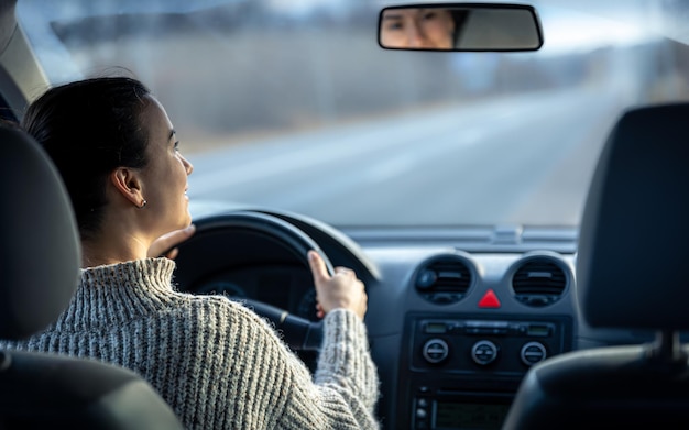 Mujer joven feliz conduce un coche vista interior