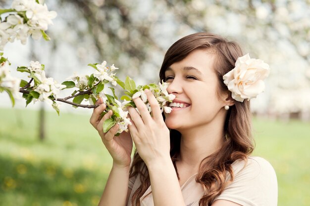 Mujer joven feliz disfrutando de la fragancia de las flores