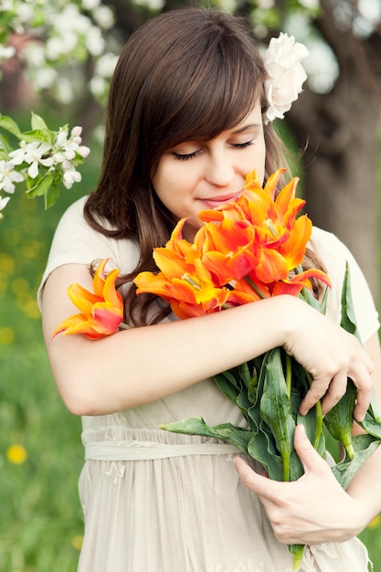 Mujer joven feliz disfrutando de la fragancia de las flores
