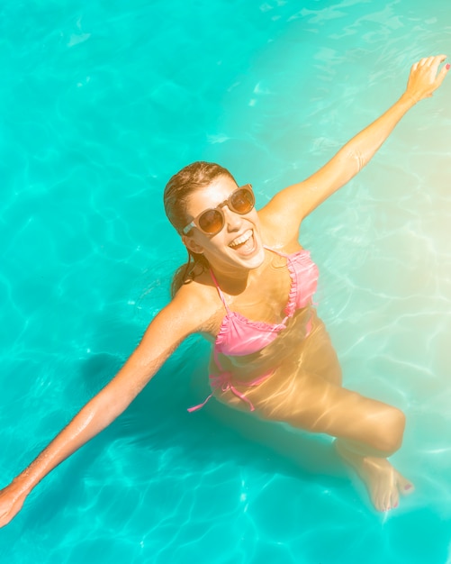 Mujer joven feliz emocionada que se coloca en piscina