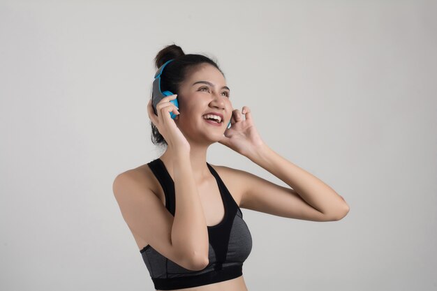 Mujer joven feliz escuchando música en auriculares aislados sobre fondo blanco