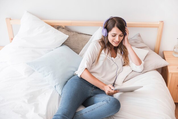 Mujer joven feliz escuchando música en la cama