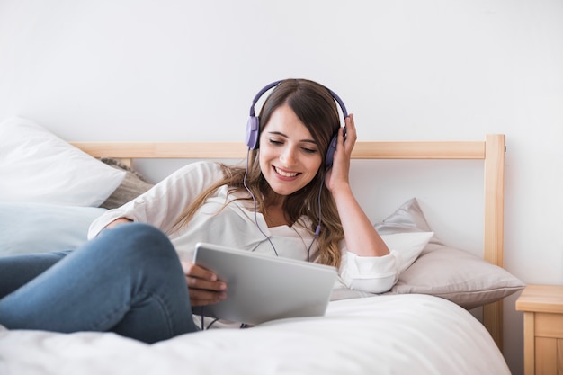 Mujer joven feliz escuchando música en la cama