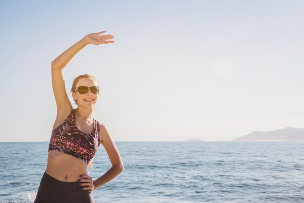 Mujer joven y feliz estirando en la playa