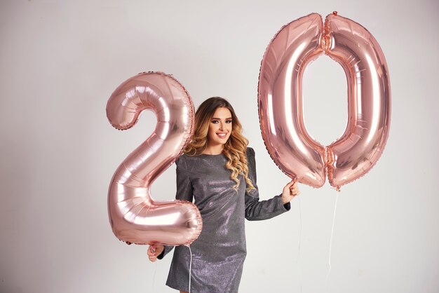 Mujer joven feliz con globos dorados celebrando su cumpleaños