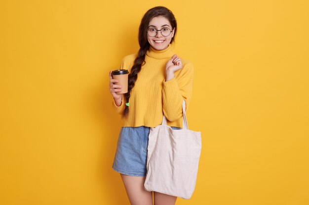 Mujer joven feliz haciendo compras y disfrutando de bebidas calientes