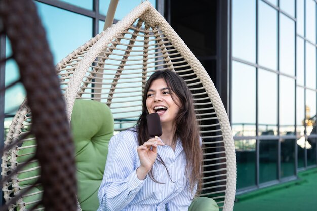 Mujer joven feliz con helado de chocolate en una hamaca