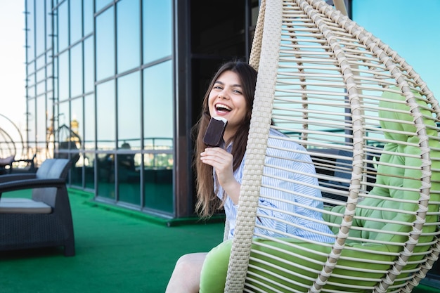 Foto gratuita mujer joven feliz con helado de chocolate en una hamaca