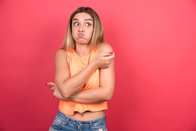 La mujer joven feliz parece sorprendida con los brazos cruzados.