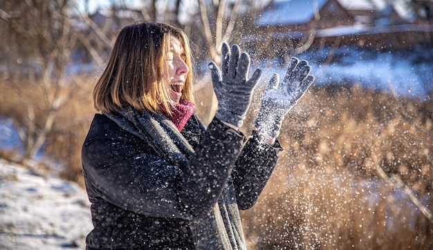 Mujer joven feliz en un paseo en invierno con nieve en sus manos