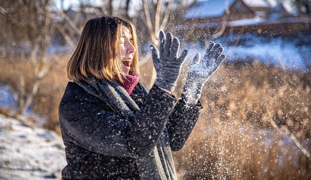 Mujer joven feliz en un paseo en invierno con nieve en sus manos