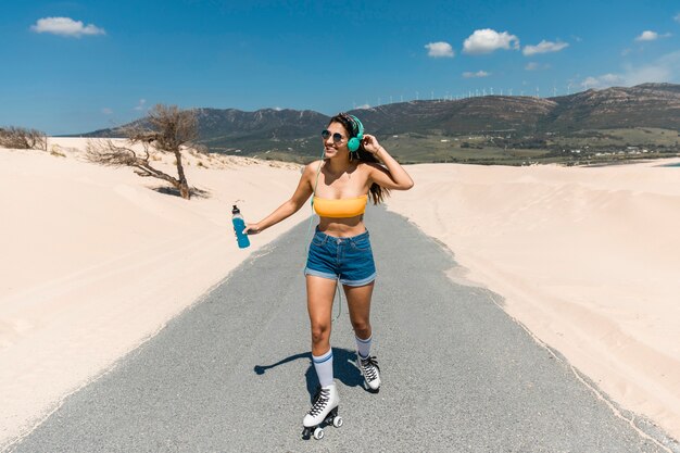 Mujer joven feliz patinando en la naturaleza