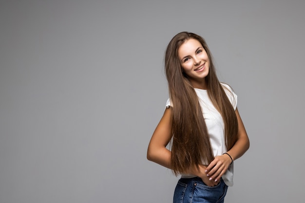 Mujer joven feliz de pie con los brazos cruzados sobre gris