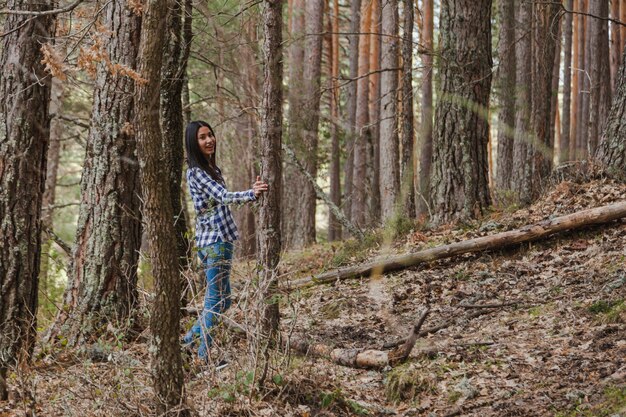 Mujer joven feliz posando junto a un árbol